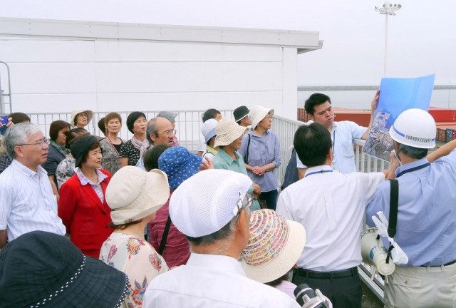 県担当者から説明を受ける田中しげひろ茨城県知事予定候補（左）と大内県議、その一行=7月25日、東海村