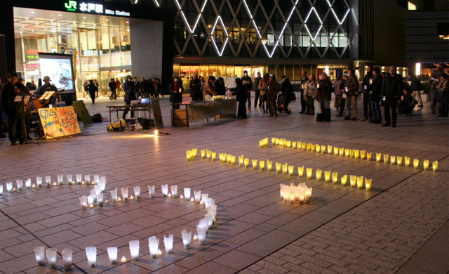 「3・11」と灯されたキャンドルを囲み、東日本大震災や原発事故について考える人たち=3月11日夜、水戸市