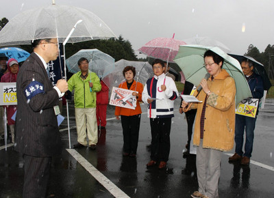 基地担当者（左）に抗議する参加者=10月22日、茨城県小美玉市・航空自衛隊百里基地正門前