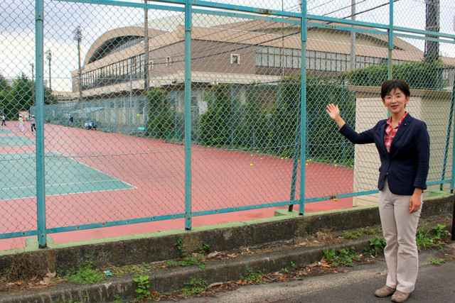 水戸市に無償譲渡される県立東町運動公園の前に立つ江尻加那県議。多くの人に利用されているテニスコートやプールはつぶされることに…