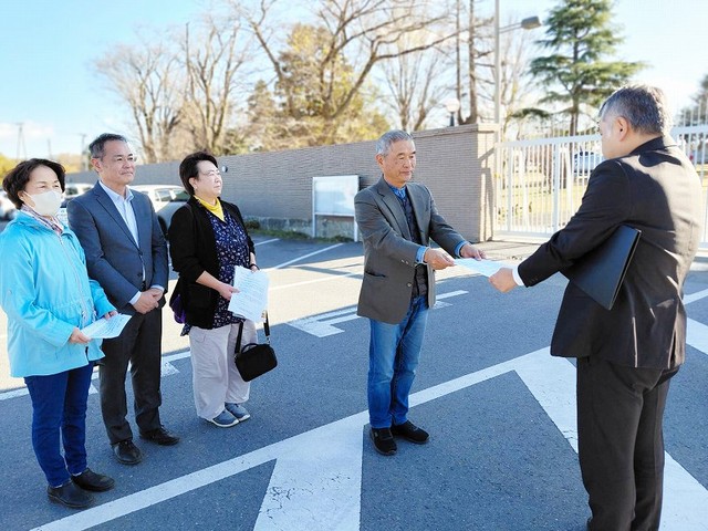 百里基地の正門前で、基地の担当者に要請書を渡す篠原氏、川井氏、上野氏、佃氏