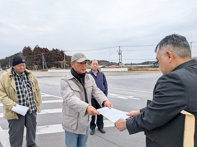 百里基地の担当者に、基地正門前の道路で要請文を渡す篠原さんと参加者