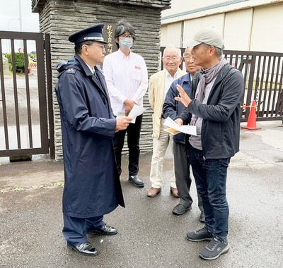 基地の正門前で自衛官へ要請書を渡し、抗議する参加者