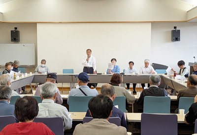 市議会の報告をする小室氏と、報告会に参加する江尻氏